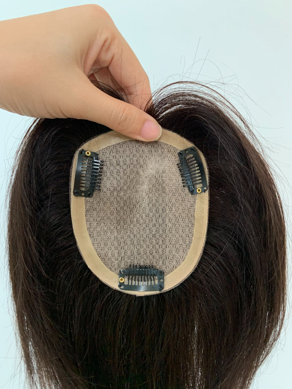 Close view of a VivaCrown silk top hair topper underside with layered center and three clips